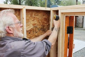 11. Attach front door wall to the front window wall and then to the floor frame with screws.